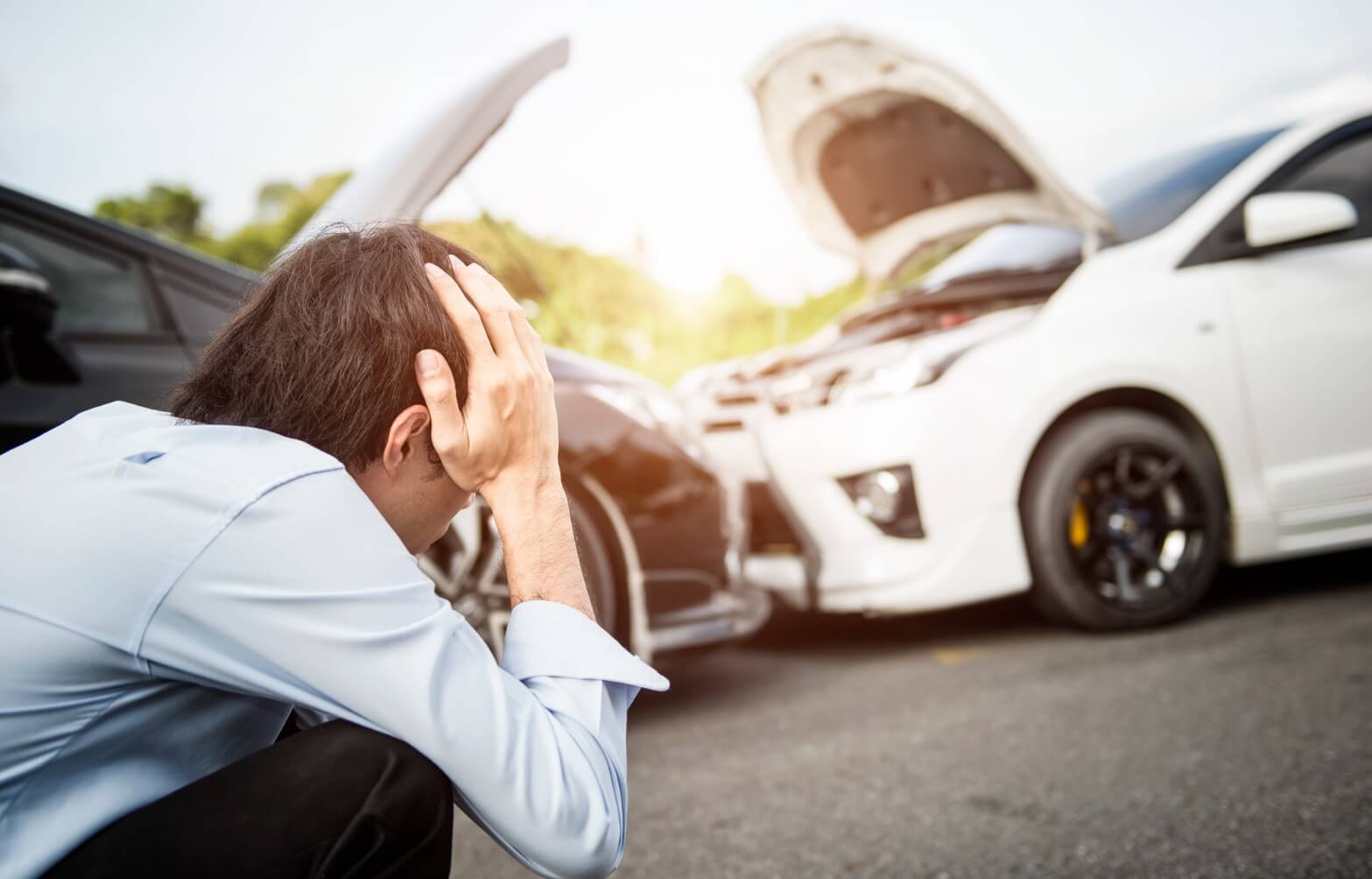 A man holding his head in front of a car crash